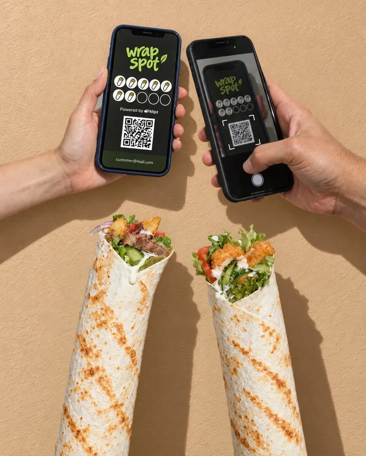 Against a sunny beige wall, the shop's phone scans the QR code on a customer's Wrap Spot membership, above two big wraps that seem to float before the wall.